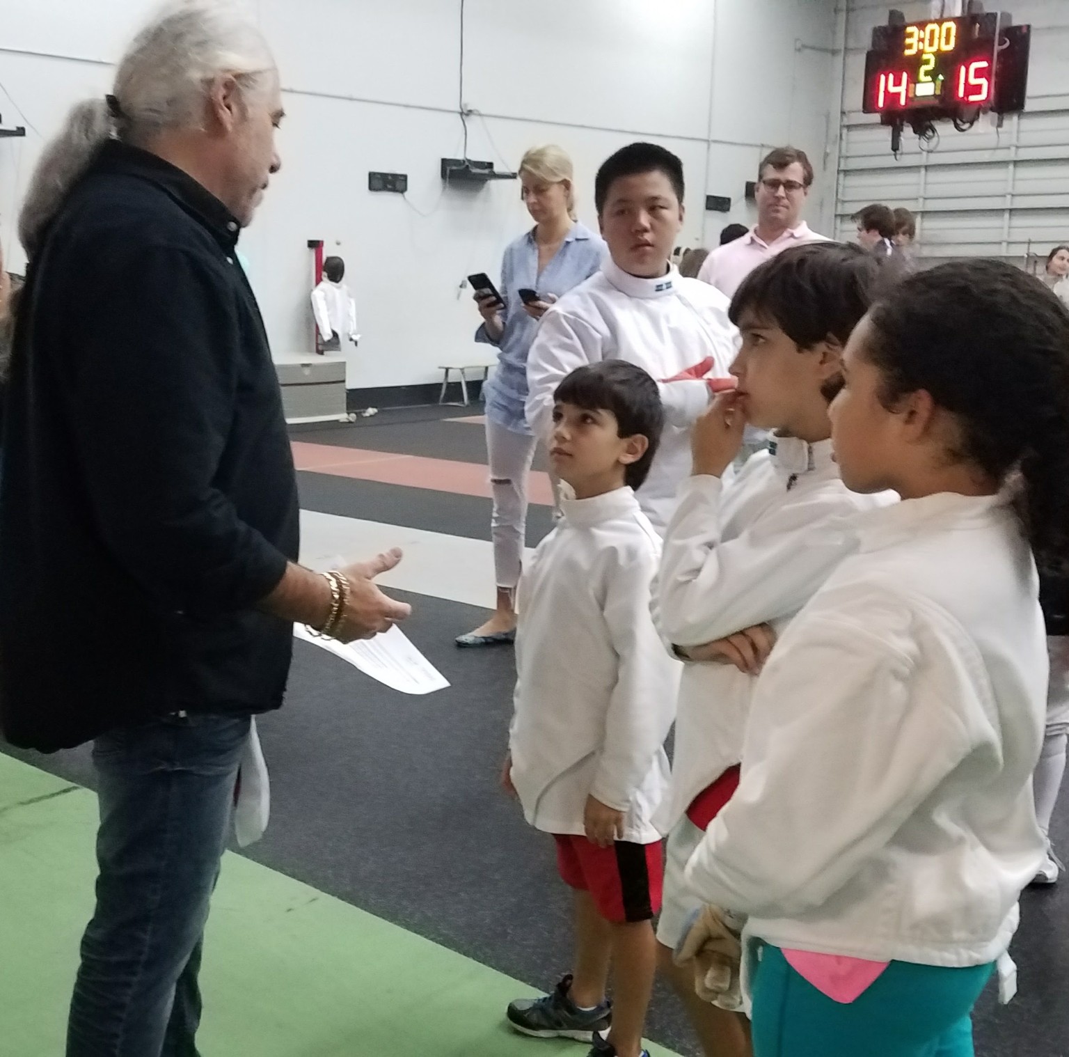 Mitch Berliner speaking with a young Benjamin Gurewich and a group of fencers